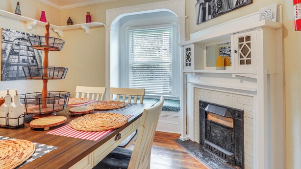 A dining area with a wooden table, chairs, and a fireplace. - Sumter Vacation Rental in Historic District! (Sumter)