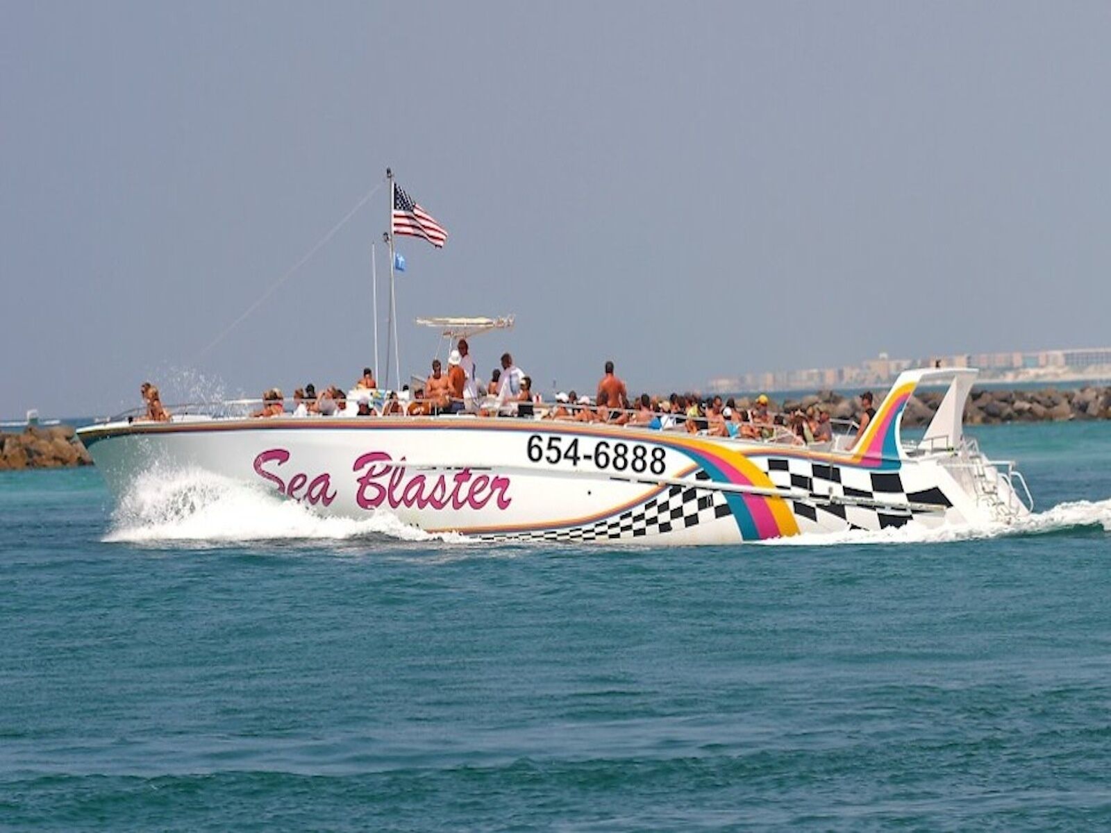 A speedboat named 'Sea Blaster' with the number 654-6888, featuring a checkered pattern and a rainbow stripe.