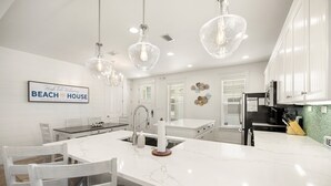 Una cocina moderna con armarios blancos, una isla de mármol e iluminación colgante.