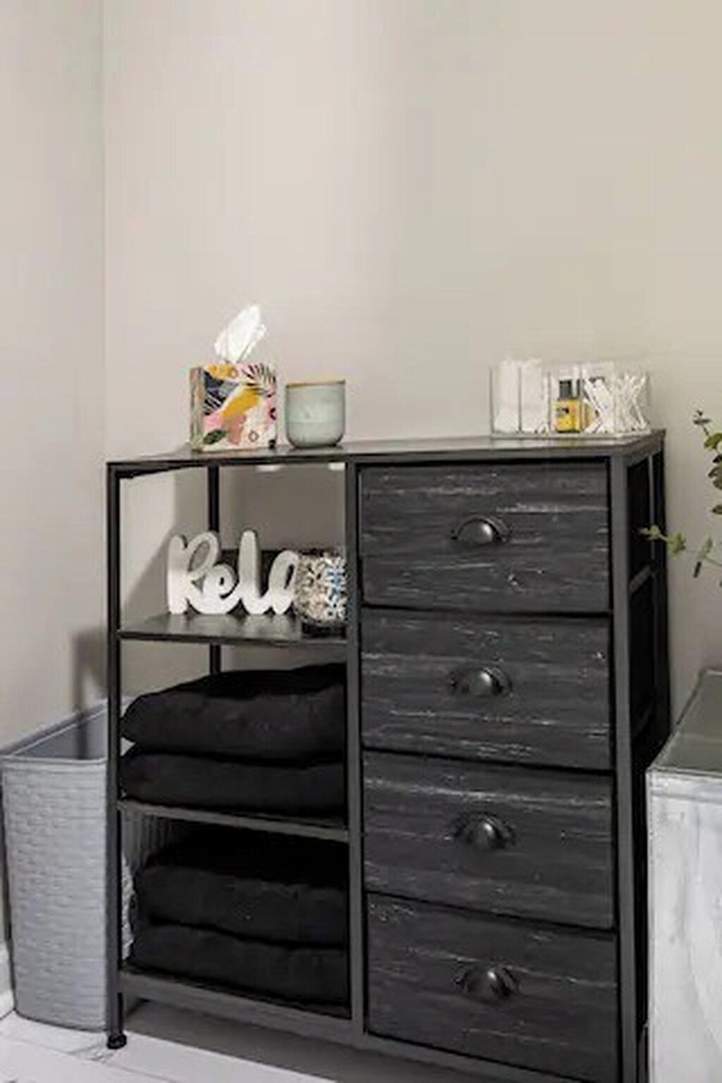 A black metal storage unit with a 'Rei' sign, a tissue box, and a small container on top.
