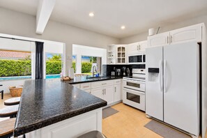 Una cocina moderna con armarios blancos, encimera de granito y horno empotrado.