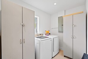 A laundry room with a washing machine, a dryer, and a Tide detergent bag. - Design Loft Home with Private Pool & BBQ, Sleeps 12, 15 Min to MIA (Miami)