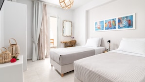 A hotel room with two beds, a desk, a chair, a large mirror, and a painting on the wall.