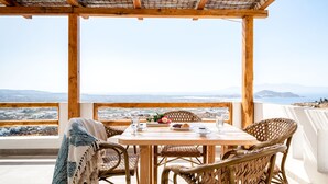 A wooden table with chairs on a balcony overlooking a scenic landscape.