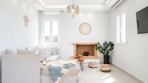A modern living room with a sofa, a fireplace, and a television mounted on the wall.