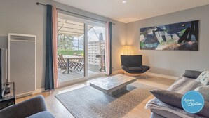 A modern living room with a sofa, a coffee table, and a chair. There is a sliding glass door leading to an outdoor patio.