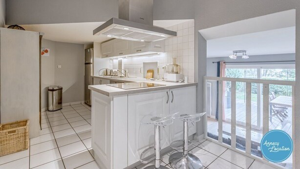 A modern kitchen with white cabinetry, stainless steel appliances, and a central island with bar stools.