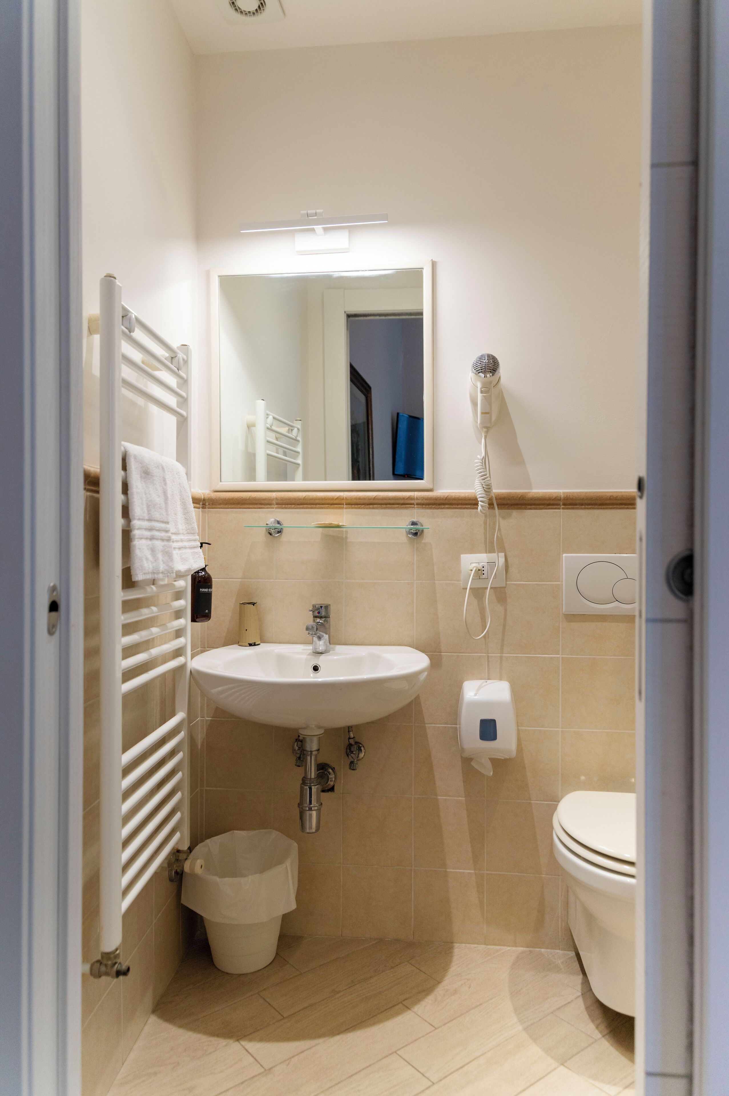 Een kleine, schone badkamer met een wastafel, spiegel, handdoekhouder en toilet.