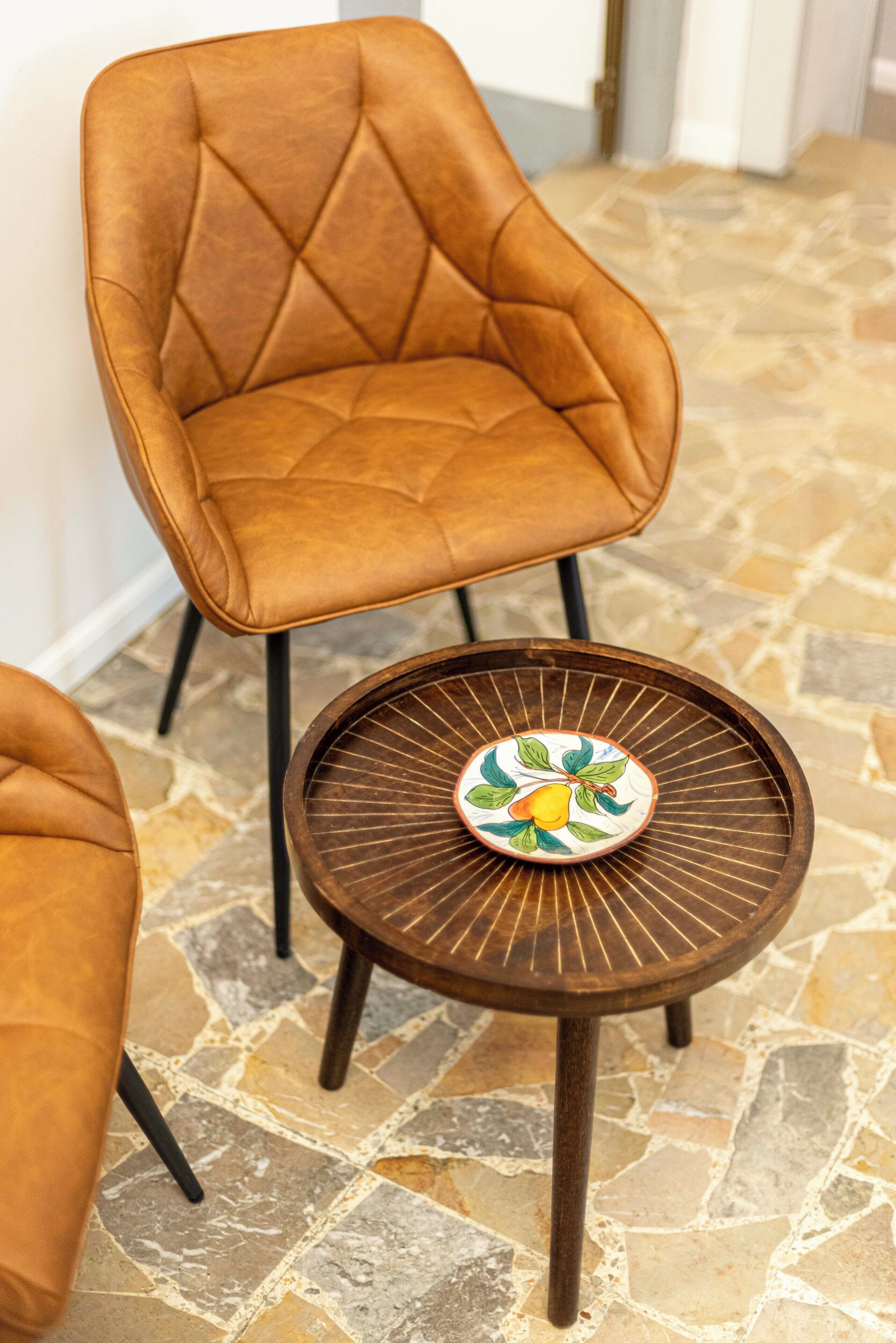 A brown leather armchair and a small round table with a decorative plate.