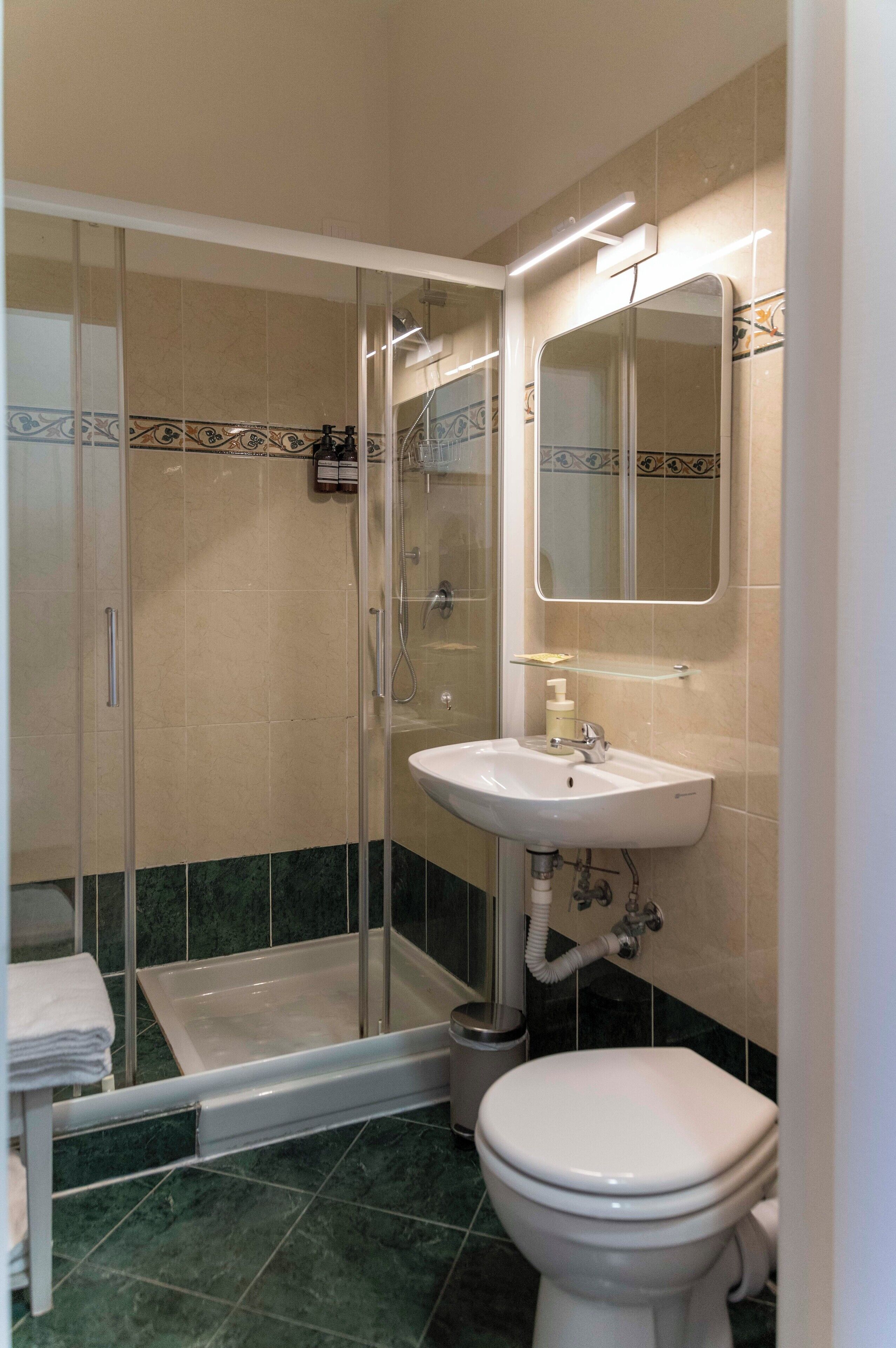 Ein Badezimmer mit Dusche, Waschbecken, Toilette und Spiegel.