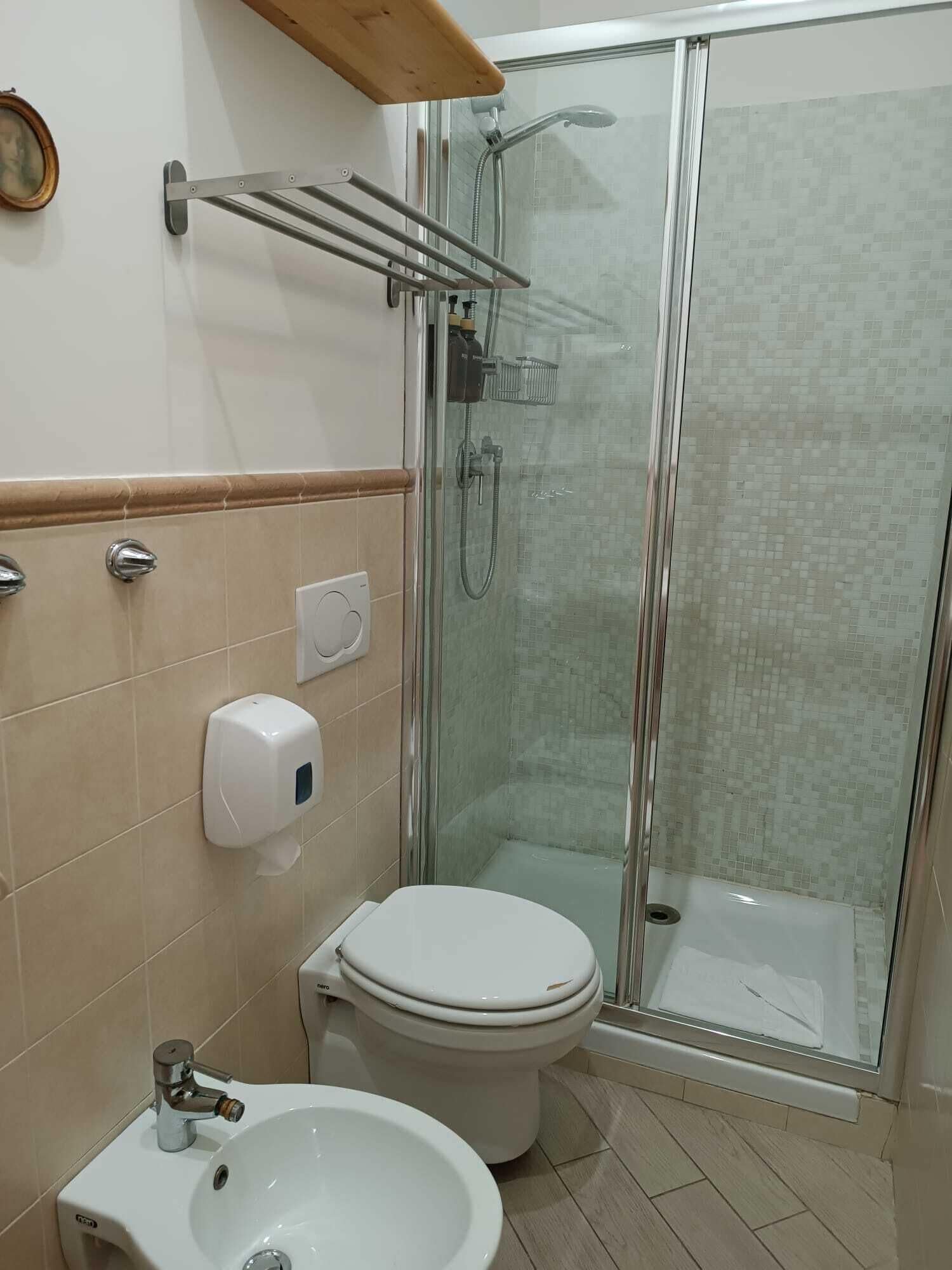 Een badkamer met toilet, bidet en douchecabine.