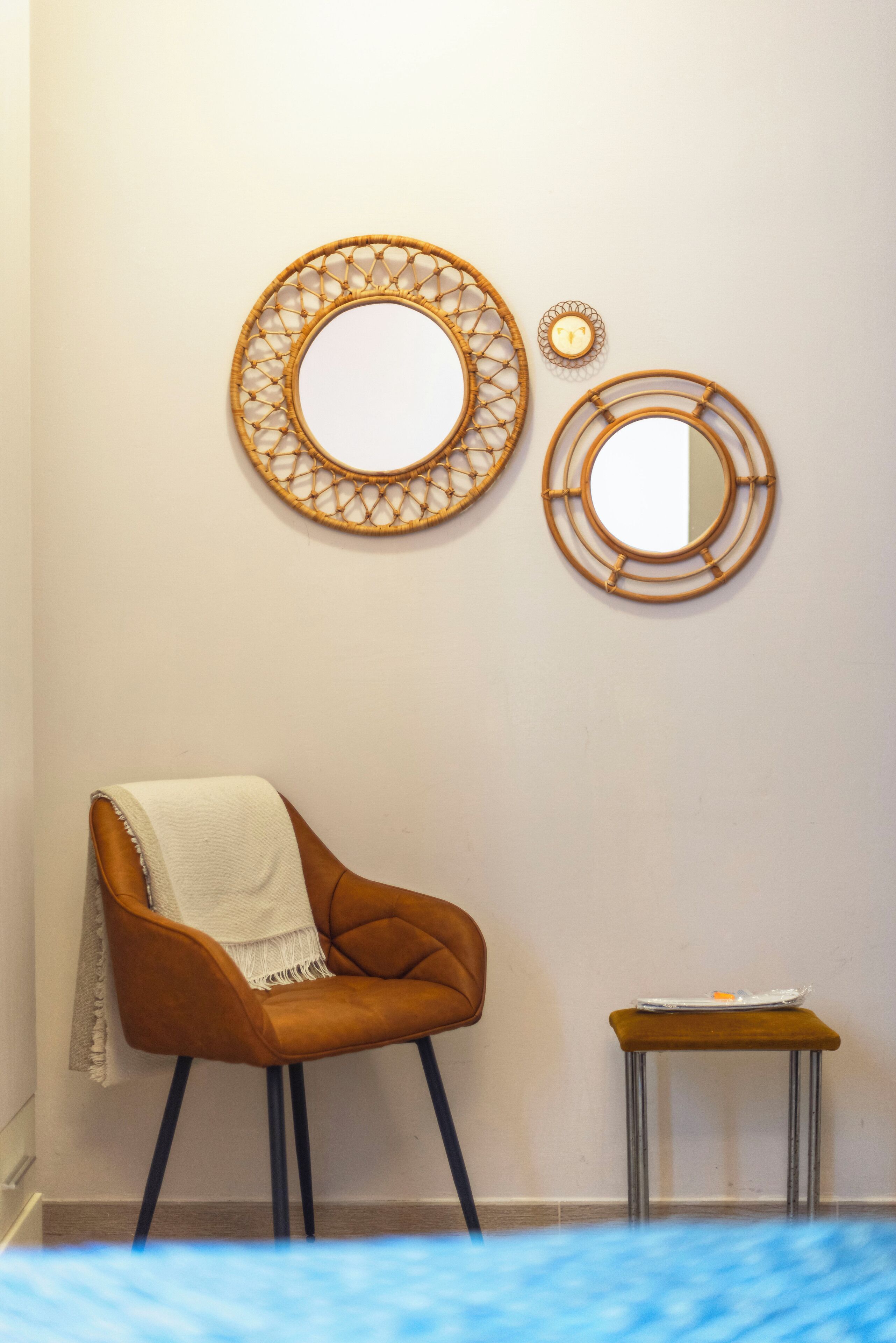 Una stanza con una sedia marrone, uno sgabello e due specchi fissati al muro.