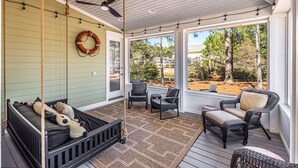 A covered porch with a bed, chairs, and a dining area. - LAKE FRONT~bonus room~GOLF CART~FREE Activites~Heated Pool* Hot tub (Miramar Beach)