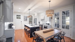 A modern kitchen with a central island, wooden dining table, and black chairs. - LAKE FRONT~bonus room~GOLF CART~FREE Activites~Heated Pool* Hot tub (Miramar Beach)