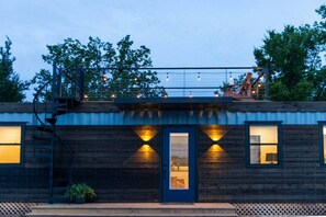 A rustic cabin with a blue door, wooden walls, and a small porch area. - Luxury Container Home | Pickleball | Rooftop Patio (Waco)
