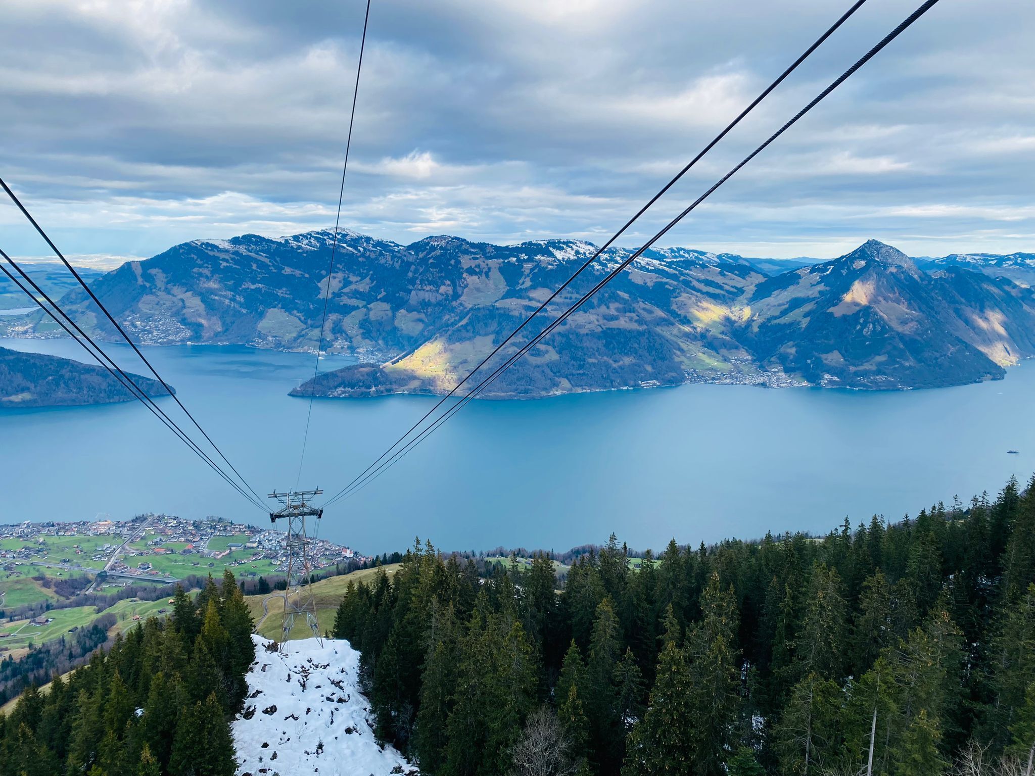 A cable car system with a mountainous landscape and a lake in the background.