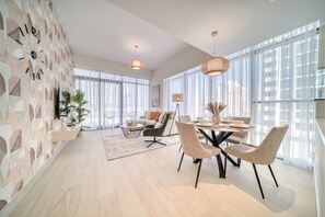 Un salon moderne avec un coin repas, de grandes fenêtres et un mur décoratif.