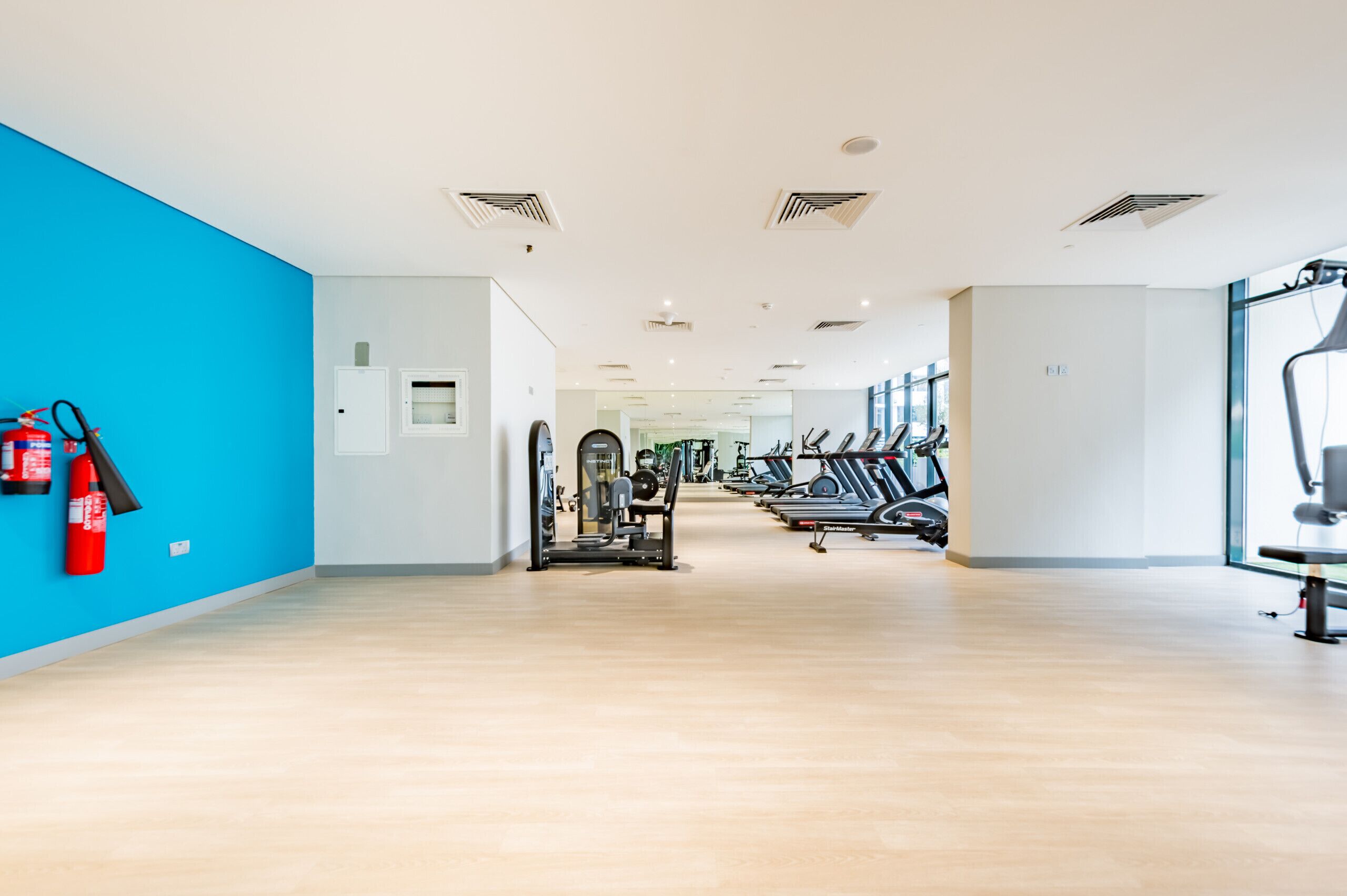 A gym with exercise equipment, a fire extinguisher, and a blue wall.