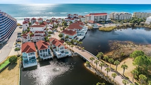 A coastal resort with beachfront villas, a marina, and a large hotel building. - Stunning Lake Views in Miramar! Golf Cart, Splash Pool, Private Beach Access! (Miramar Beach)