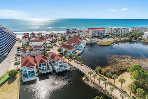 A coastal resort with beachfront villas, a marina, and a large hotel building.