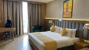 Habitación de hotel con una cama grande, un escritorio, una silla y un cuadro en la pared.