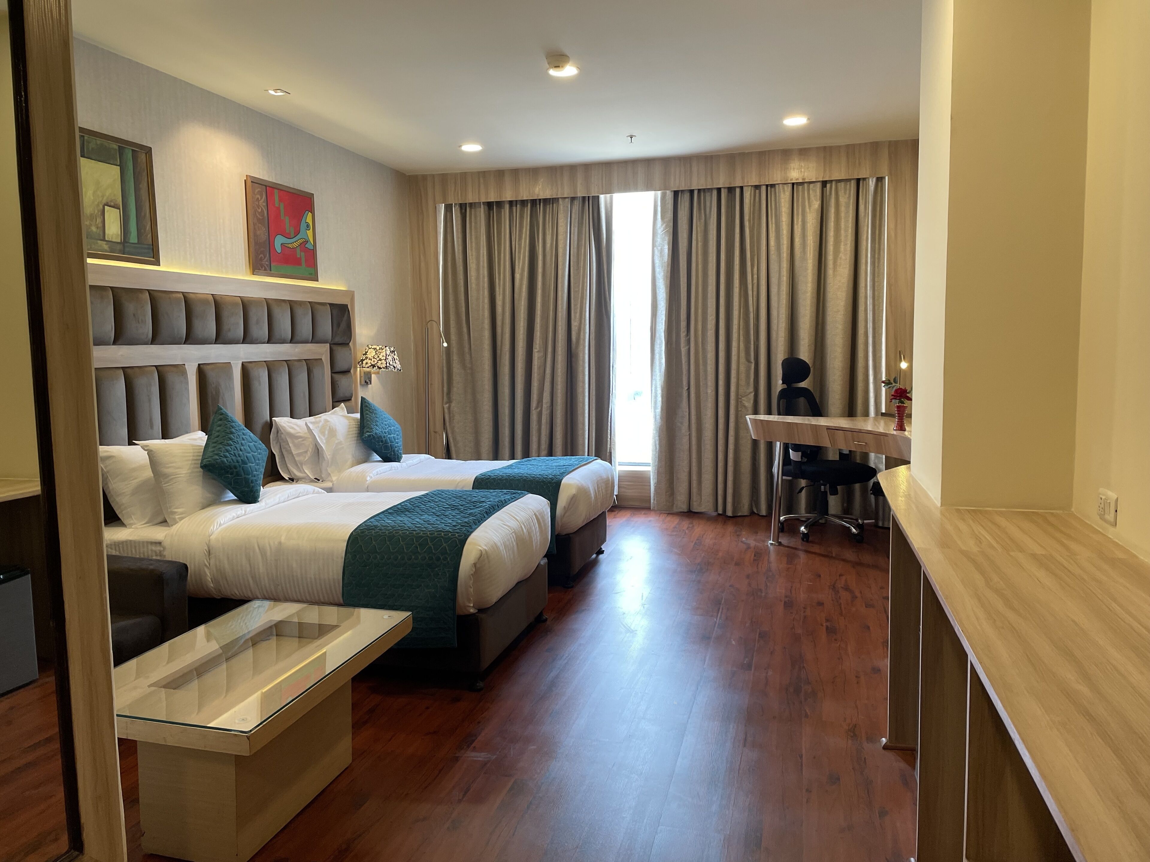 Habitación de hotel con dos camas, un escritorio y una silla.
