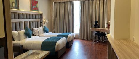 Habitación de hotel con dos camas, un escritorio y una silla.