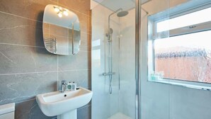 A modern bathroom with a glass-enclosed shower, a large mirror, and a sink with toiletries. - Host & Stay | St Mark's Close (Marske-by-the-Sea)
