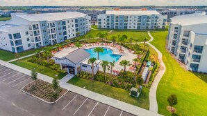 A modern hotel complex with multiple buildings, a central swimming pool, and surrounding greenery. - 3121-108 Resort Lake View Disney Universal Orlando (Kissimmee)