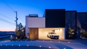 Een modern huis met een witte auto op de oprit in de schemering.