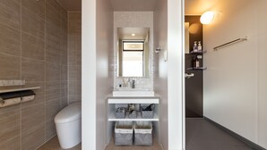 Een kleine badkamer met een wit wastafelmeubel, spiegel en opbergmanden.