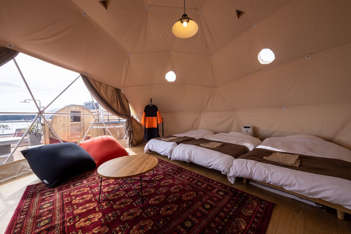 Ein Zeltraum mit Bett, einem kleinen Tisch und Blick ins Freie.