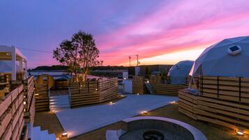 Una azotea con zonas de estar de madera, un hogar y vistas al atardecer.