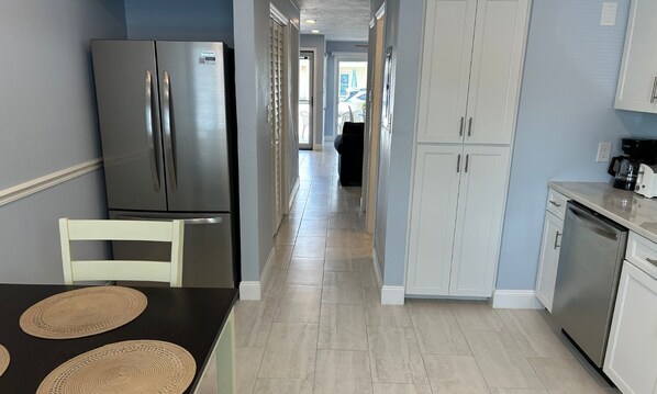 A kitchen with a stainless steel refrigerator, white cabinets, and a coffee maker on the counter.
