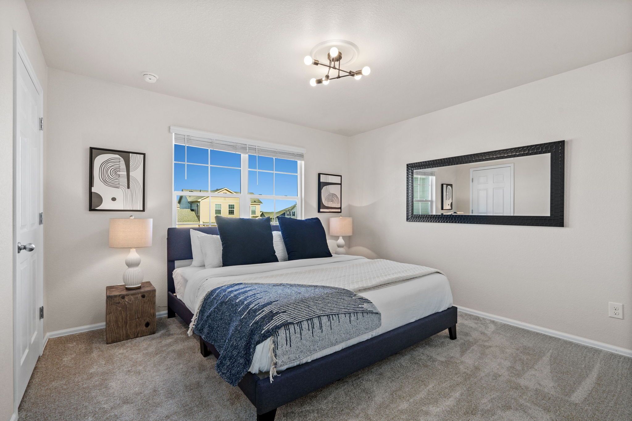 A bedroom with a bed, bedside lamps, a window, and a ceiling light fixture.