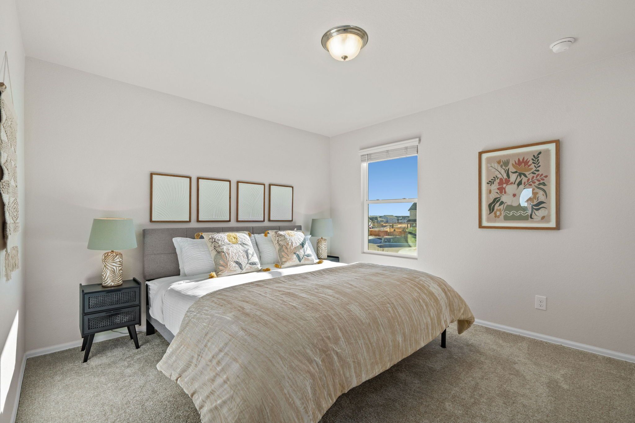 Quarto com cama, mesas de cabeceira, janela com vista e quadros nas paredes.