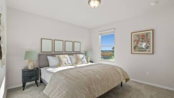 Quarto com cama, mesas de cabeceira, janela com vista e quadros nas paredes.