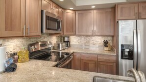 A kitchen with wooden cabinets, stainless steel appliances, granite countertops, and a built-in oven.