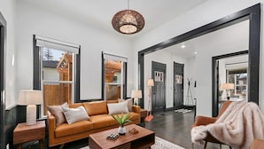 A modern living room with a leather sofa, wooden coffee table, and a large mirror. - Old Town Retreat w/ Hot Tub Steps From Csu! (Fort Collins)
