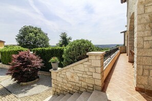 Staircase leads to a charming outdoor space with lush greenery and a low stone wall.