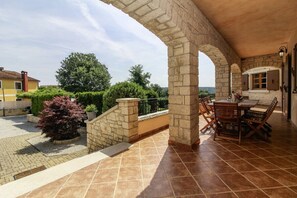 Relax in a serene outdoor space with a stone archway, comfortable seating area, and lush greenery.