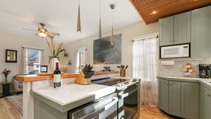 A modern kitchen with a central island, stainless steel appliances, and a microwave above the cabinets. - Lavish Retreat in Old Town - Walk Everywhere! (Fort Collins)