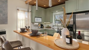 A modern kitchen with a wooden countertop, stainless steel appliances, and a large window. - Lavish Retreat in Old Town - Walk Everywhere! (Fort Collins)