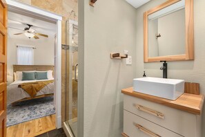 A modern bathroom with a white sink, wooden countertop, and a large mirror. - Lavish Retreat in Old Town - Walk Everywhere! (Fort Collins)