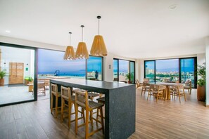 A modern interior with a bar area, seating, and large windows offering a city view. - Modern 1BR | Walk to Beach & Boardwalk (Puerto Vallarta)