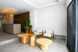 A modern lobby with a reception desk, wooden furniture, potted plants, and a staircase. - Modern 1BR | Walk to Beach & Boardwalk (Puerto Vallarta)