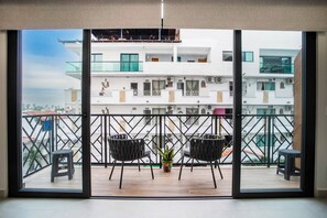 A balcony with two chairs and a small table, overlooking a white building with multiple floors and balconies. - Modern 1BR | Walk to Beach & Boardwalk (Puerto Vallarta)
