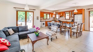 Amplia sala de estar con sofá, mesa de comedor y cocina al fondo.
