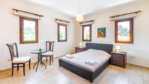 Un dormitorio con una cama, dos sillas, una mesita pequeña y dos mesitas de noche con lámparas.