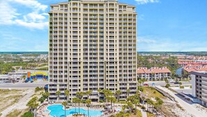 A high-rise hotel with multiple balconies, a swimming pool, and a view of the surrounding area.